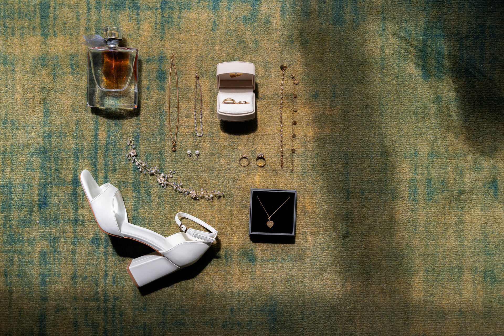 Schuhe, Parfum und Schmuck der Braut auf dem Teppich