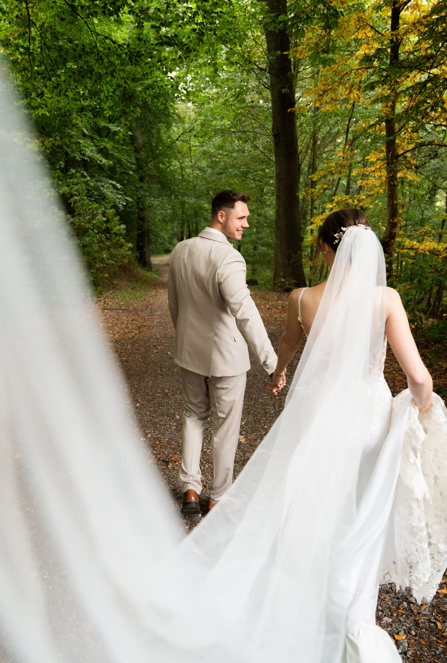 Brautpaar auf dem Waldweg hinter der Villa Vue, der Schleier zieht über den Boden