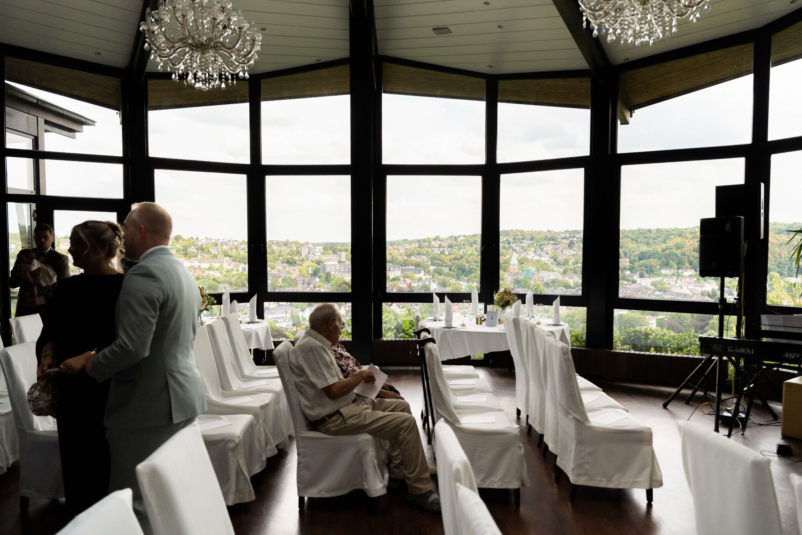 Gäste kommen im Saal der Villa Vue an, hinter den Fenstern der Blick ins Tal